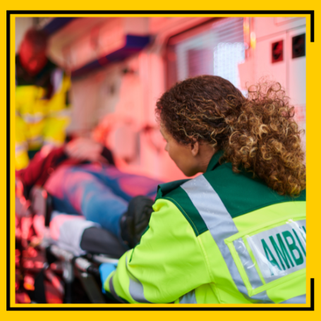 Ambulance crew loading stretcher patient into the back of an ambulance.